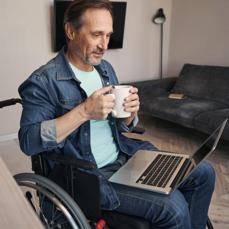 Man in wheelchair looking at laptop | Pfizer clinical trials